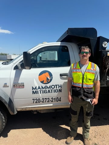 Jack of Mammoth Mitigation standing in front of a company truck in safety gear